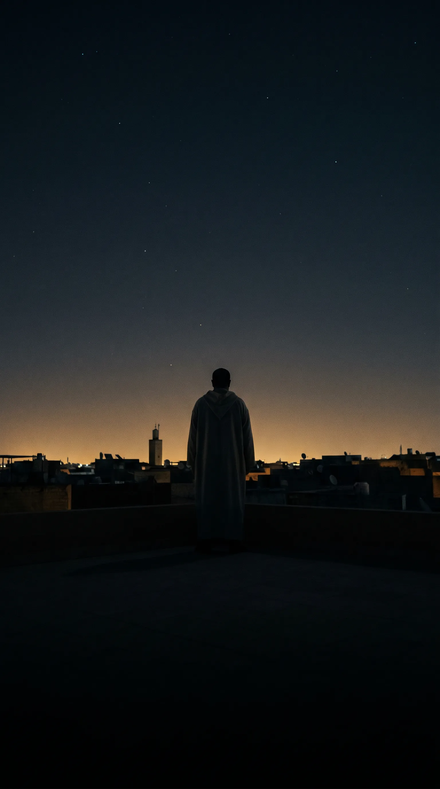 A Muslim standing on a rooftop beneath the sky before dawn